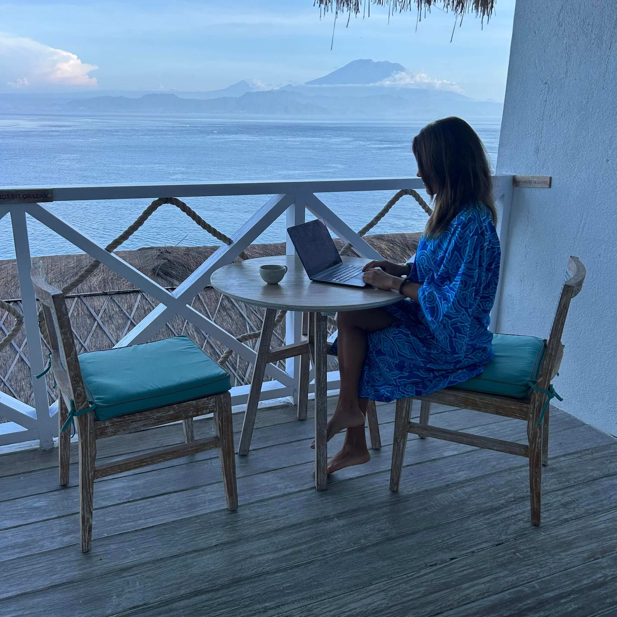 jasmina-planning-travel-details-sea-view Jasmina planning travel details at a table overlooking the sea